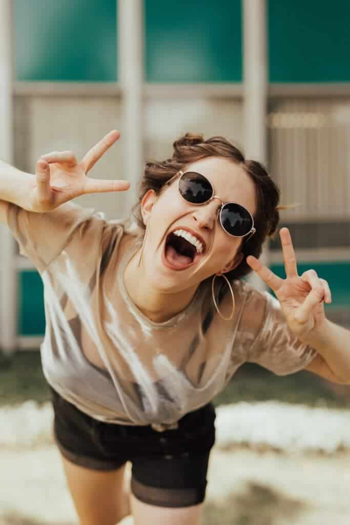 Woman wearing sunglasses holding up the peace sign