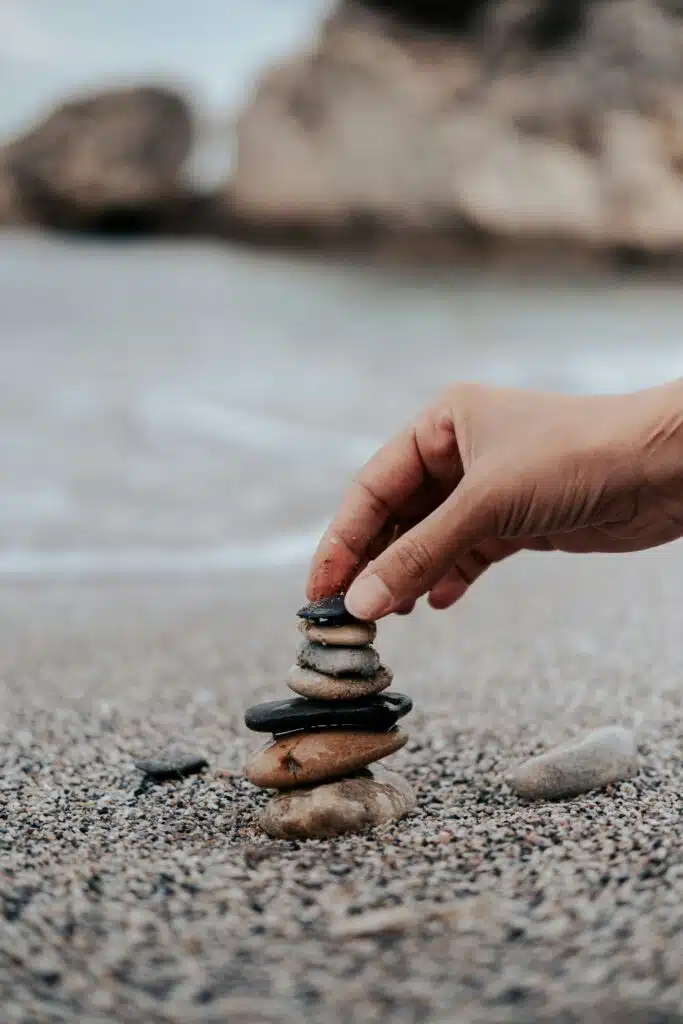 A hand oilling rounded stones on top of each other