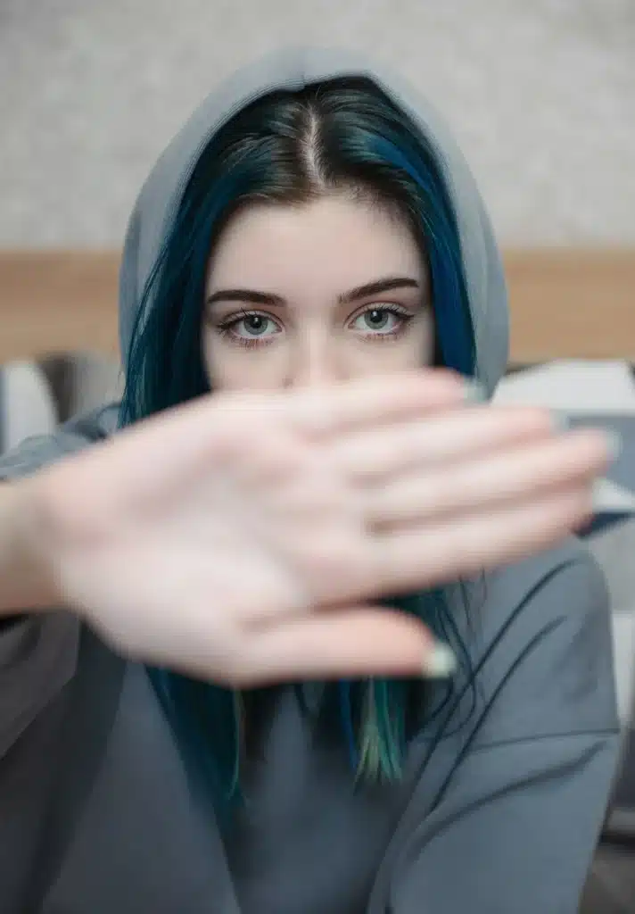 A teenage girl with blue hair is sad and depressed.