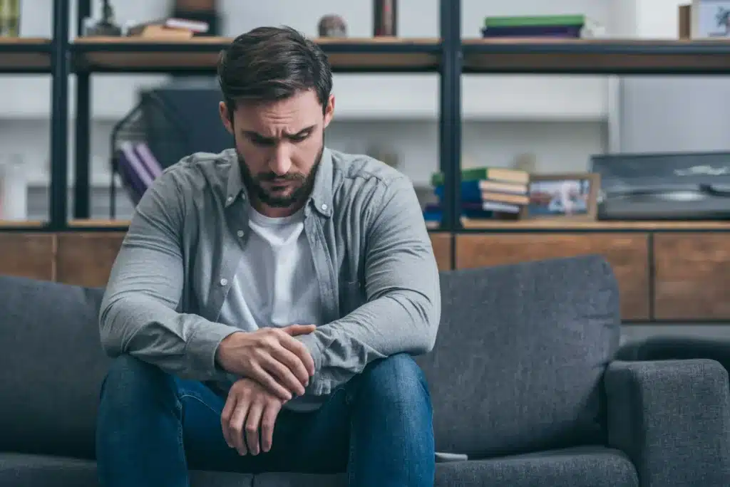 depressed man sitting and grieving on couch in living room