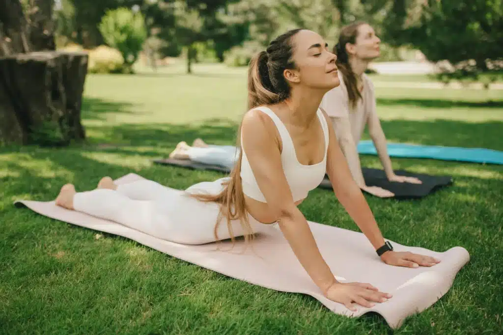 Group of millennial women having group yoga class in a park. Healthy lifestyle.