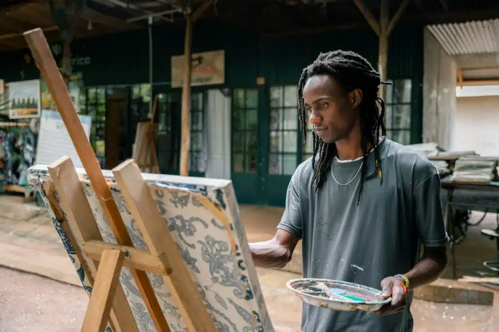 African american fine arts student paints in an outdoor classroom