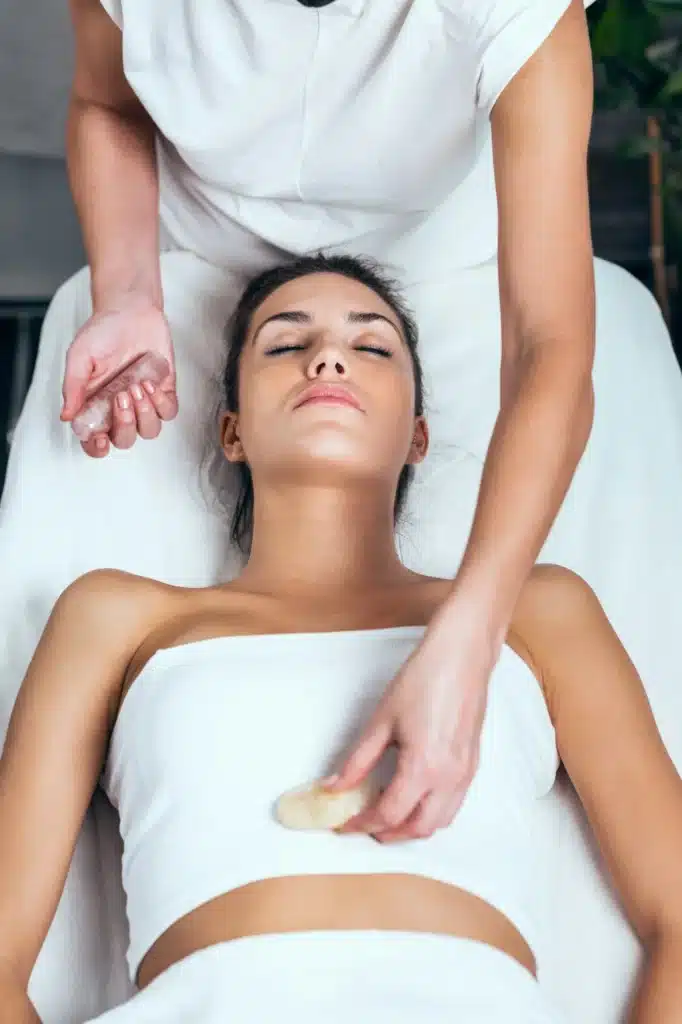 Beautiful young woman having reiki healing treatment in health spa center