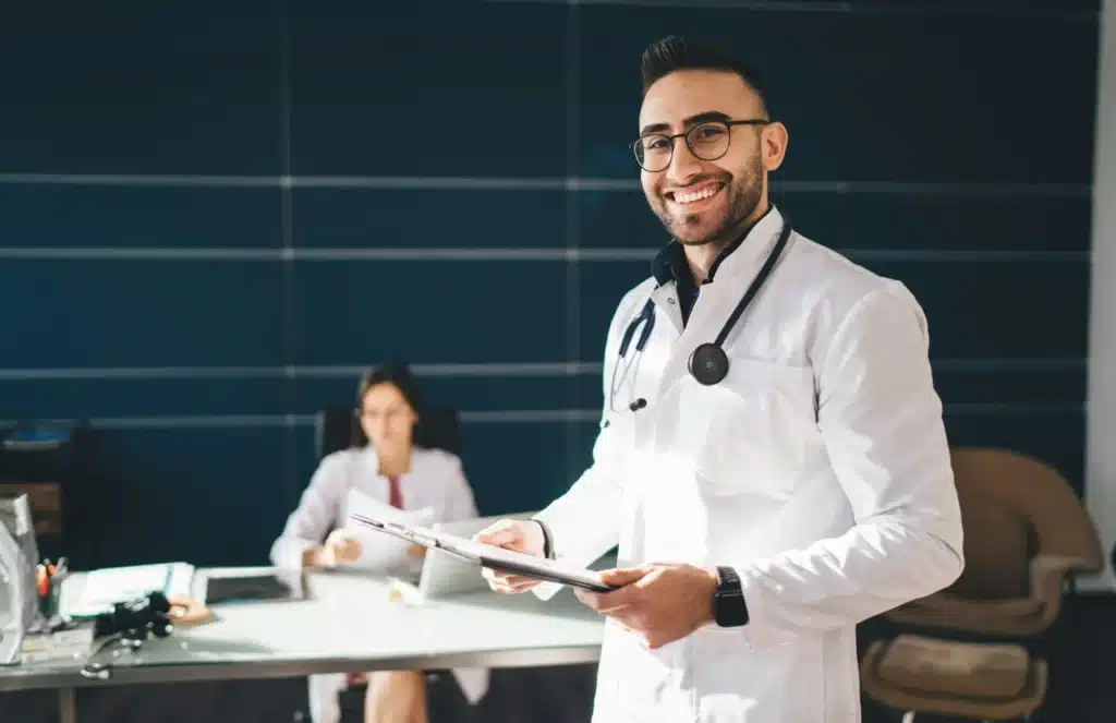 Cheerful male doctor in medical uniform working in hospital