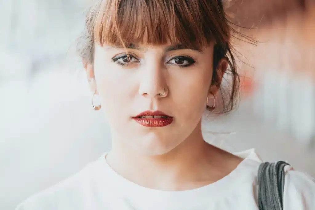 Close up portrait of a young woman looking straight to camera with a serious face and red lips