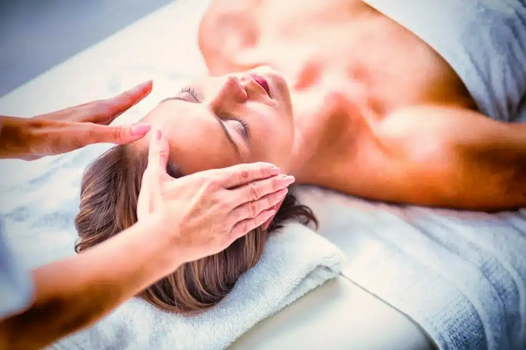 Cropped hands of therapist performing reiki on woman