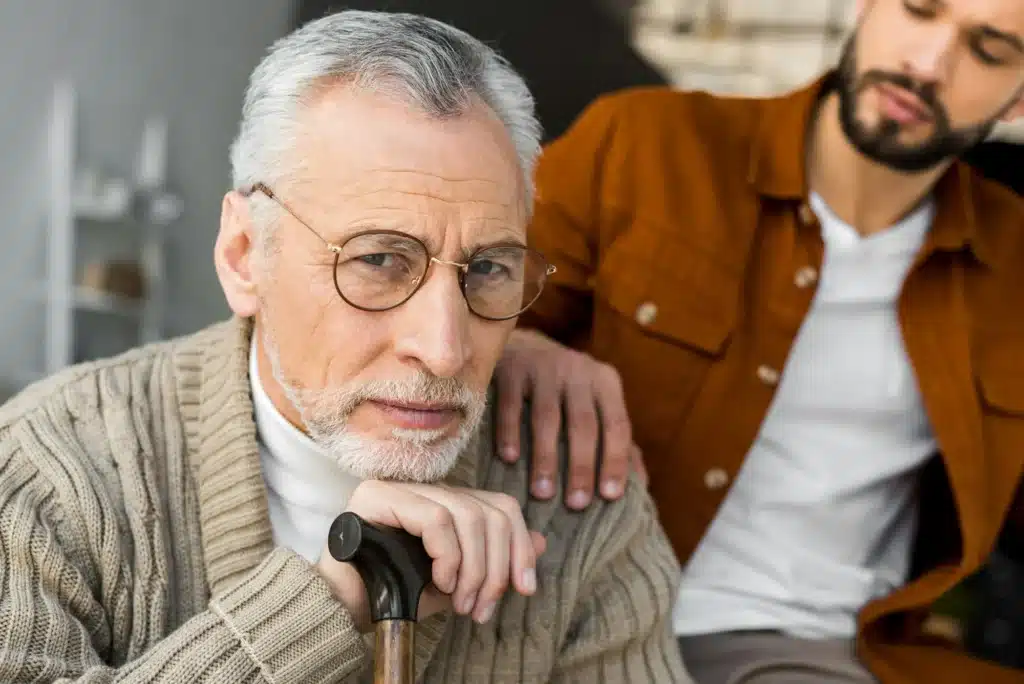 cropped view of bearded son putting hand on shoulder of sad senior father in glasses