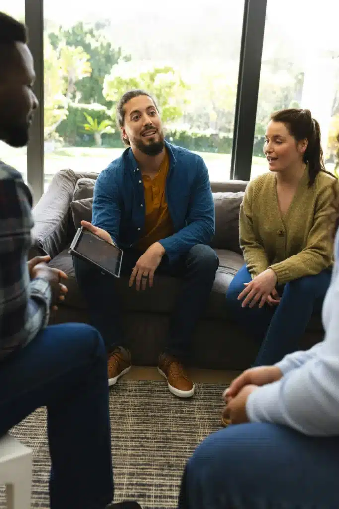 Diverse group of friends and male therapist with tablet in group therapy session