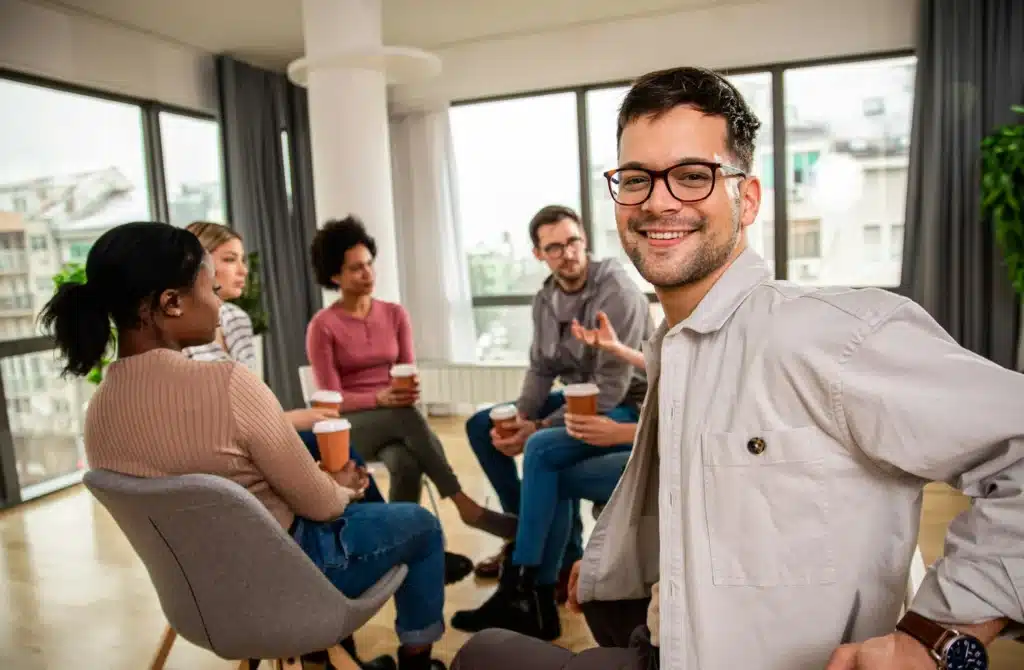 Diverse group of people sitting in circle in group therapy session.