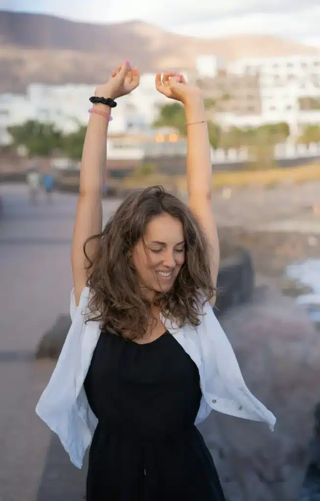 Free happy woman arms up praising freedom at sunset