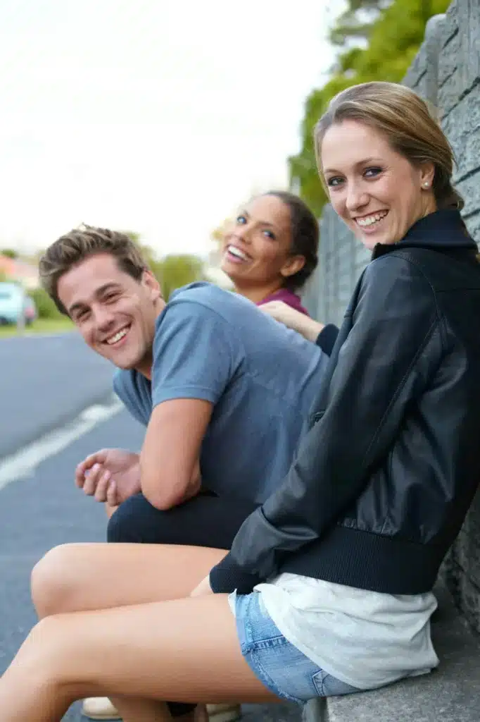 Fun with friends. Portrait of three young friends sitting on a roadside bench.