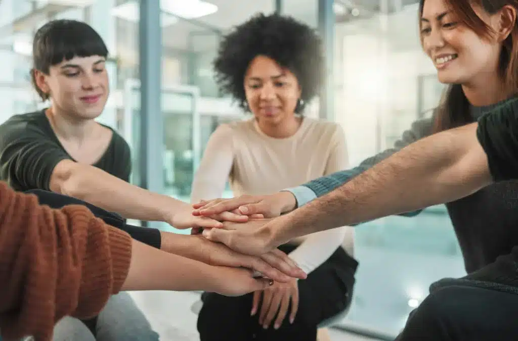 Happiness begins here. Shot of people stacking their hands during a aa therapy session.