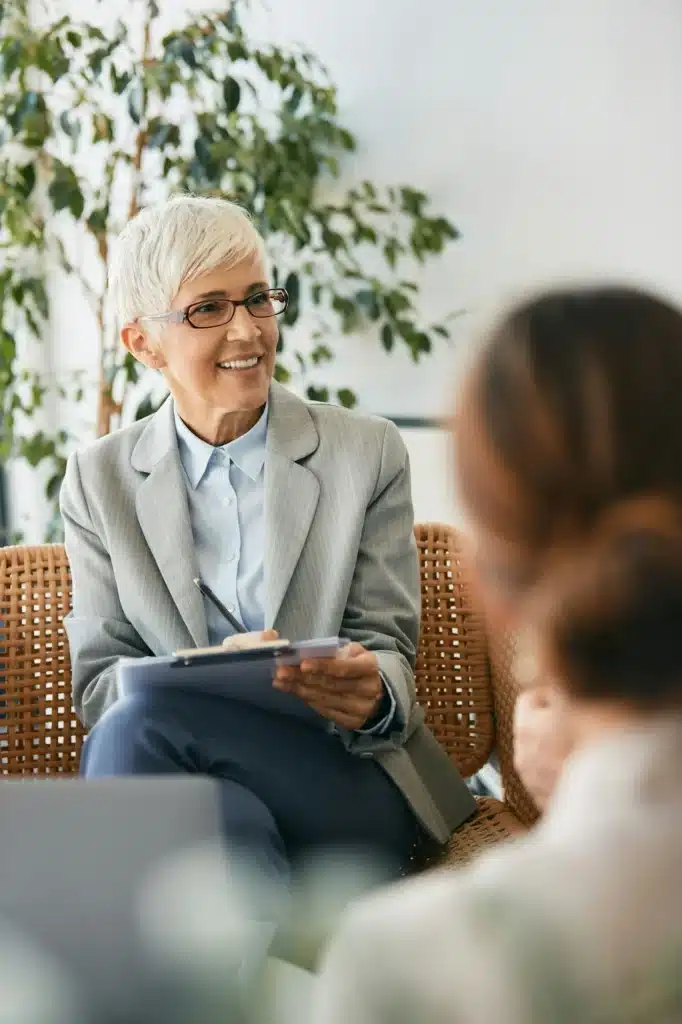 Happy mature insurance agent taking notes during a meeting with her clients in the office.