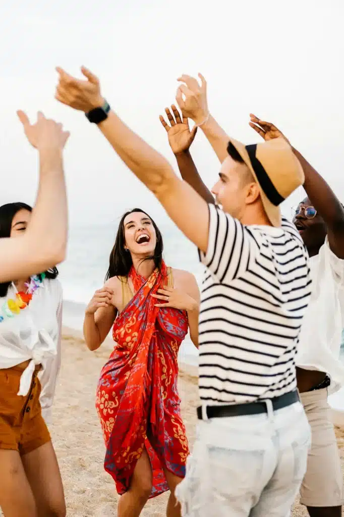 Happy young friends dancing on summer party at beach