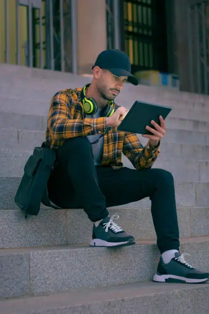 Man in a cap works remotely with a tablet at night