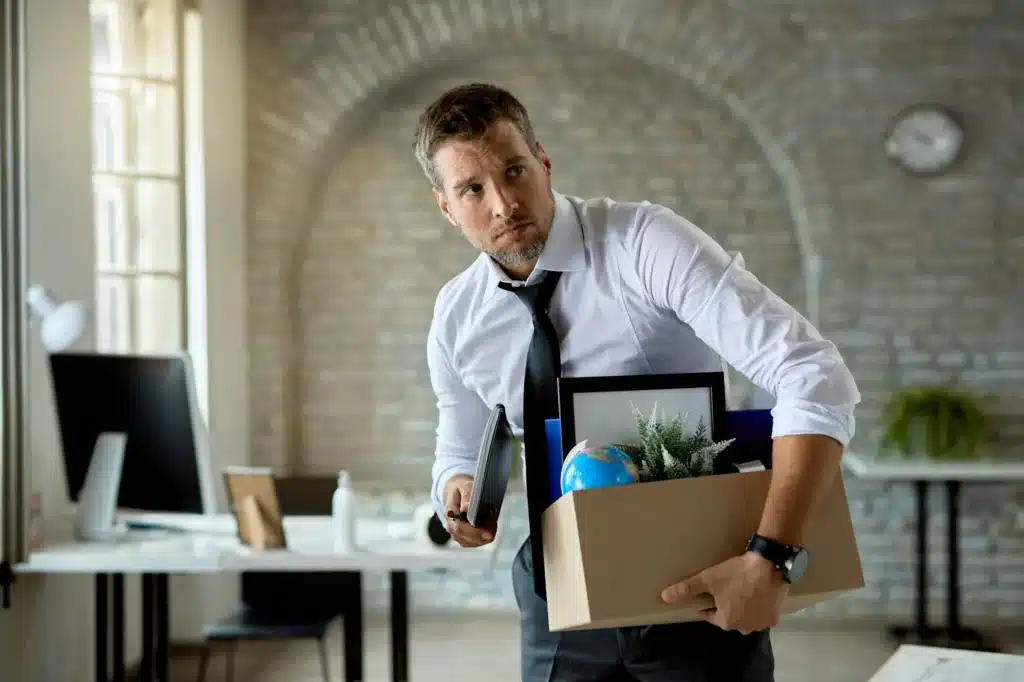 Mid adult businessman carrying his belongings office after getting fired at work.