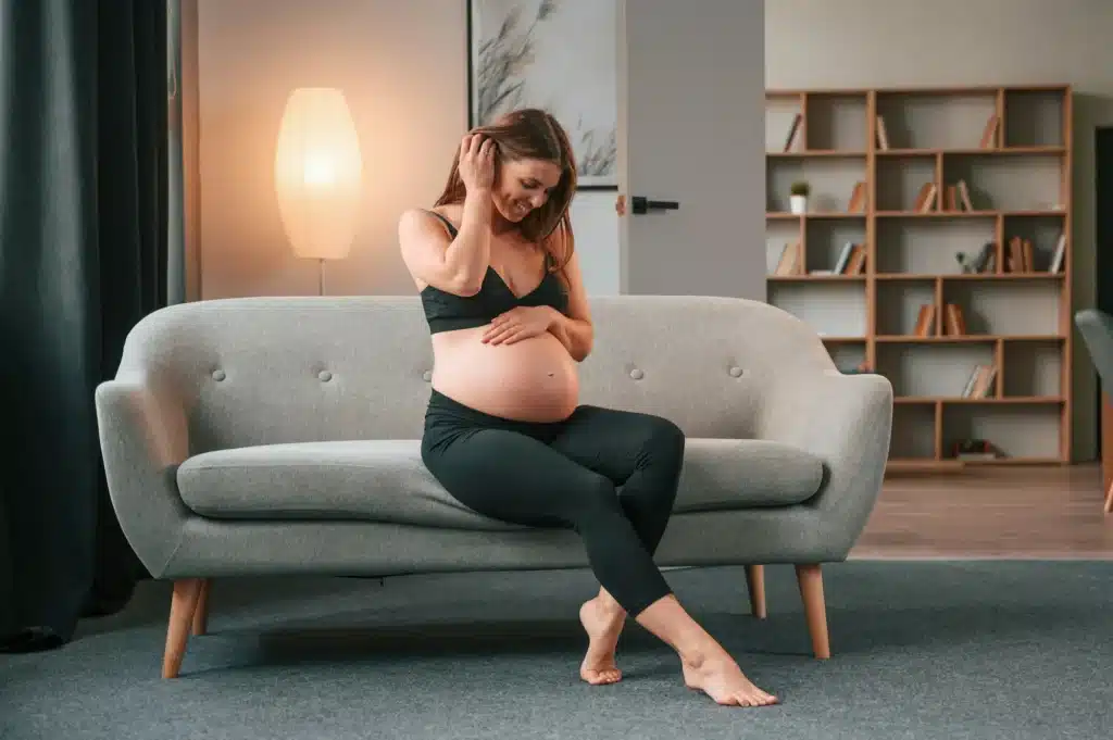 On the sofa. Beautiful pregnant woman is indoors at home