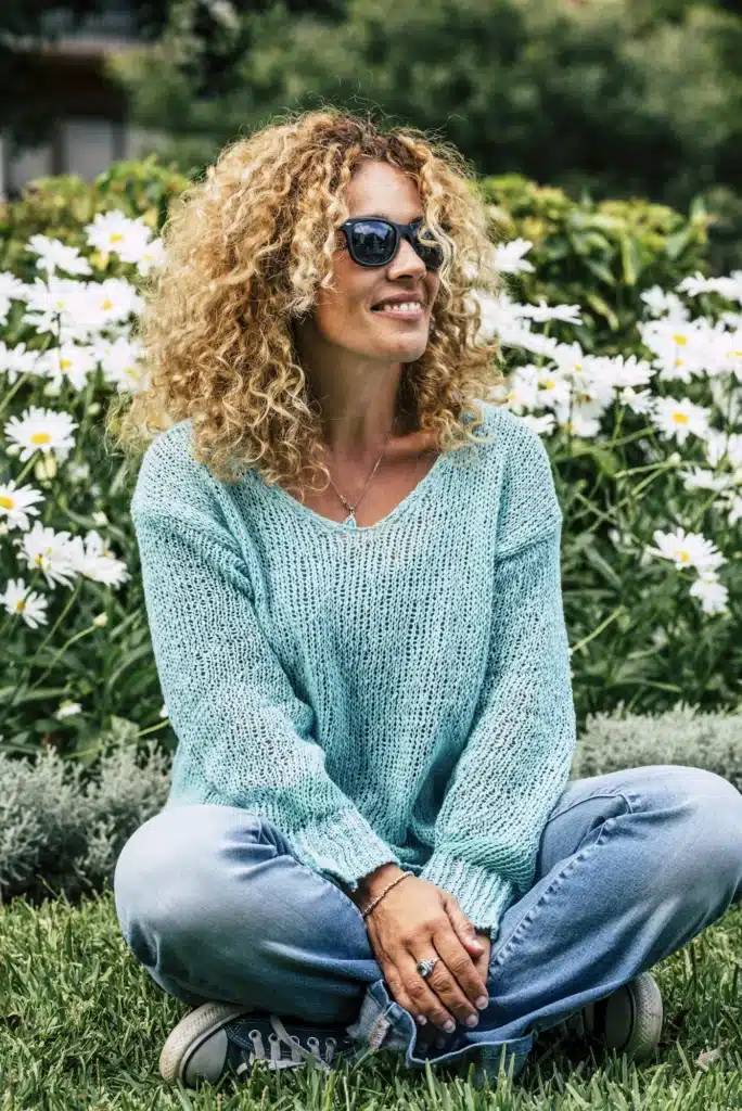 One woman enjoying outdoor park sitting on the grass and smiling. Springtime and happy people.