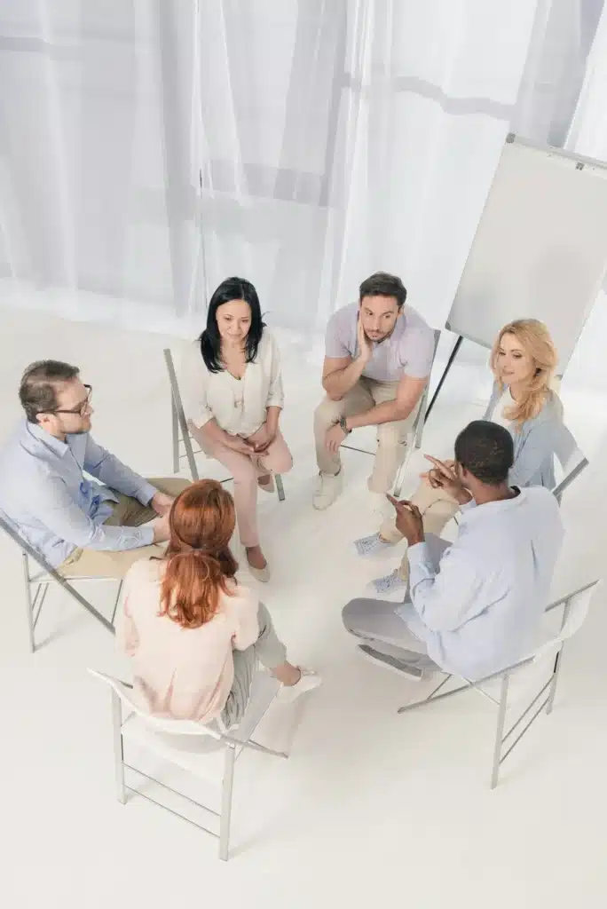 overhead view of multiethnic middle aged people sitting on chairs and talking during group therapy