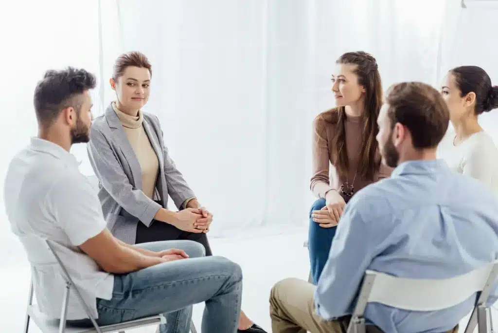 people sitting in circle during support group therapy meeting