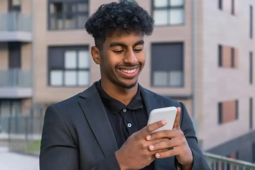 Portrait of a happy arab man using phone outdoors