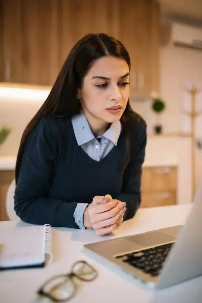 Portrait of an frustrated worried young woman while looking at laptop.