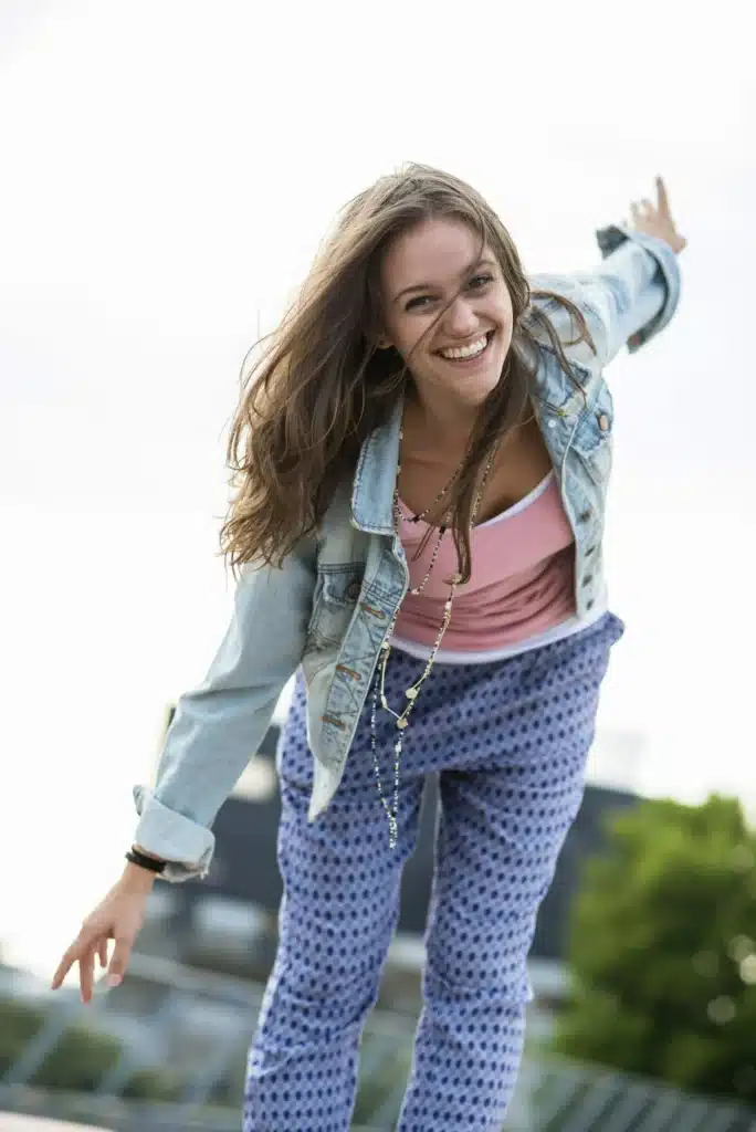 Portrait of smiling teenage girl balancing with outstretched arms