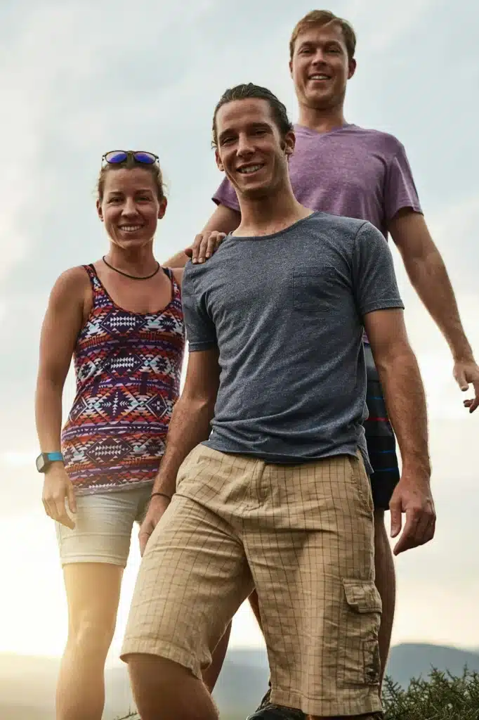 Portrait of three happy friends posing together during a hike in the mountains