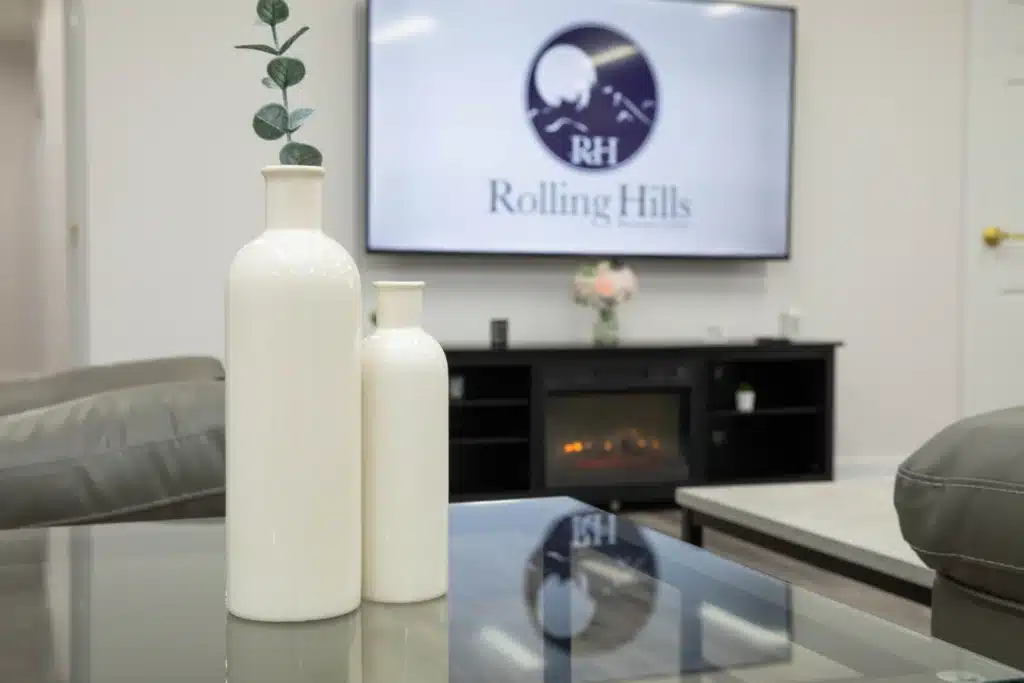 vase sitting on a glass table with rolling hills recovery center logo on the tv in the background.