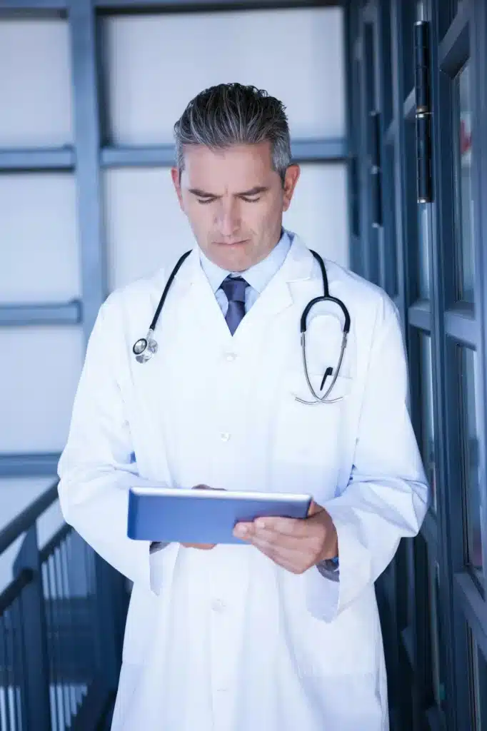 Serious male doctor using digital tablet in the hospital