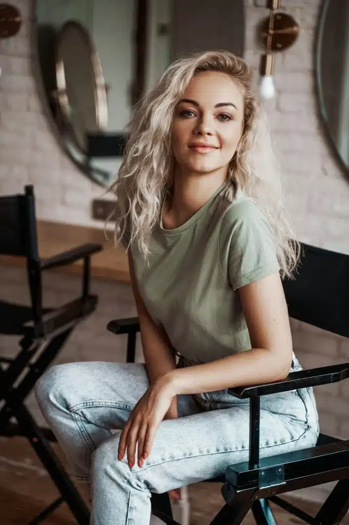 Smirking and lovely woman sitting in a make up studio on a tall chair in front of round mirrors