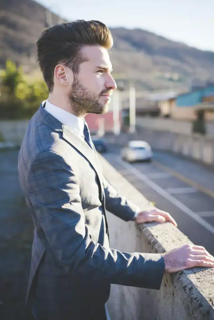 Stylish young man looking out from roadside wall