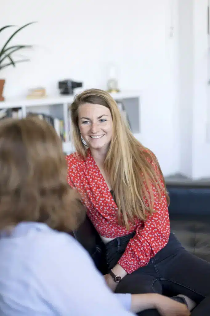 Two friends talking and laughing on a sofa in the living room at home