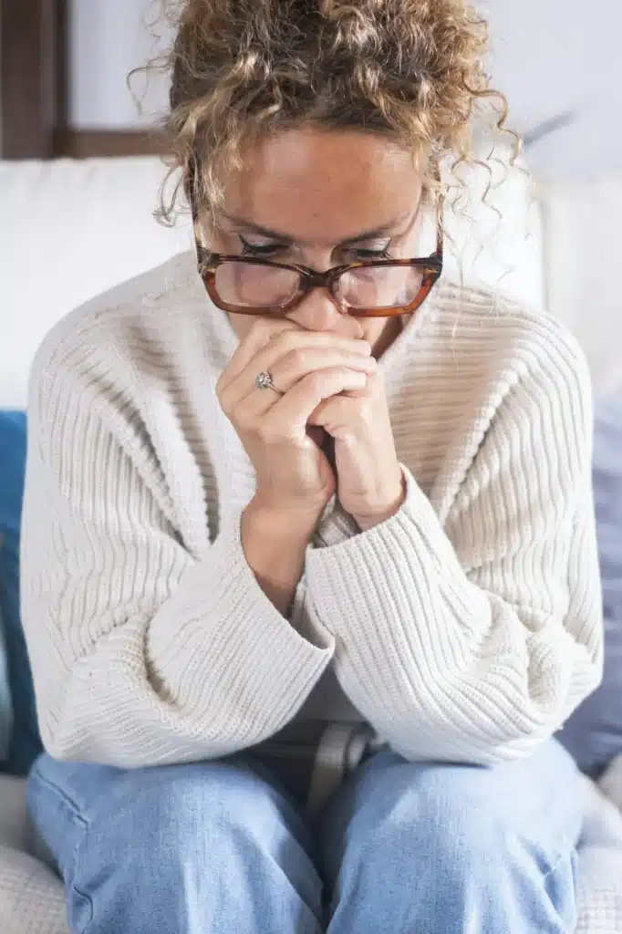 Unhappy adult lonely woman indoor sit on sofa at home and looking at window, thinking