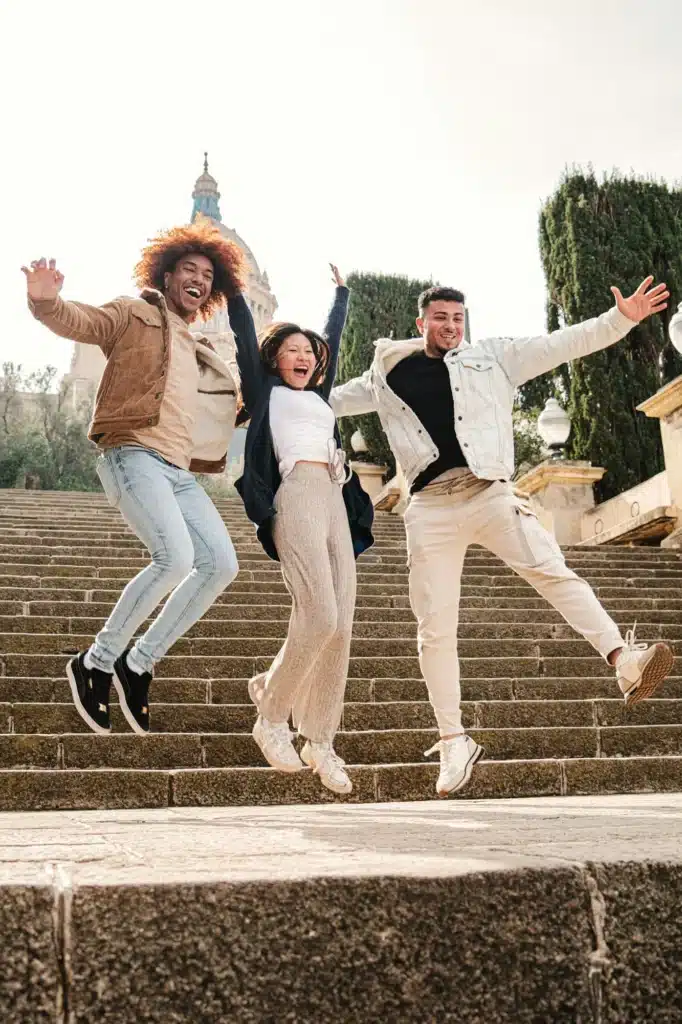 Vertical portrait. Group of multiracial happy friends having fun jumping on the street spreading