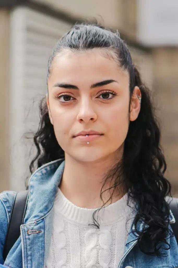 Vertical portrait of young hispanic serious girl brunette student looking serious at camera