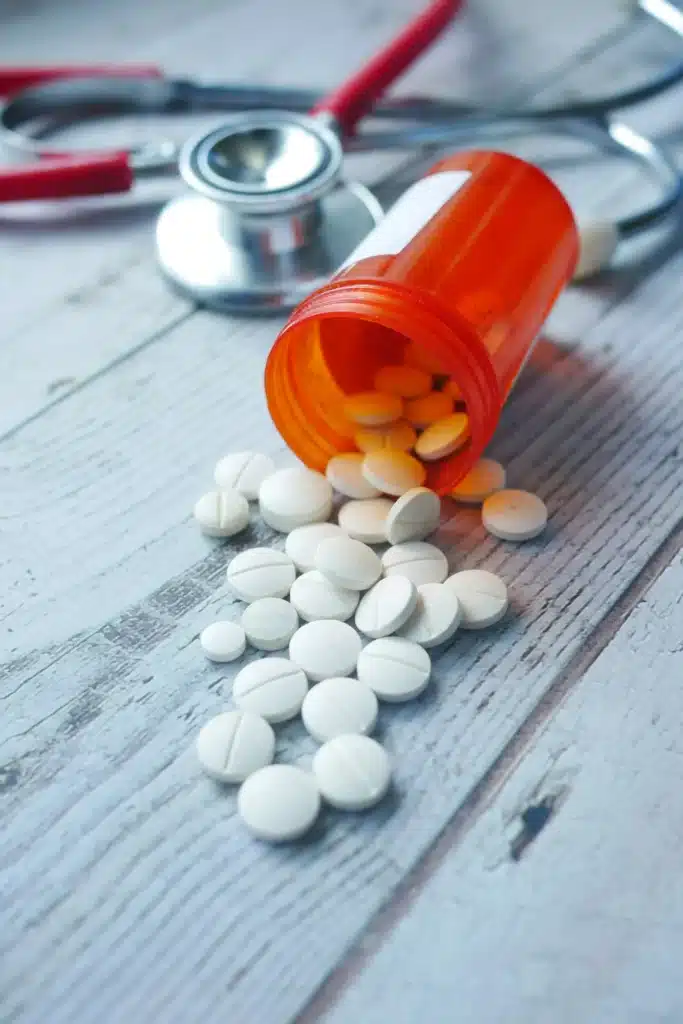 white color medical pills spilling on wooden table