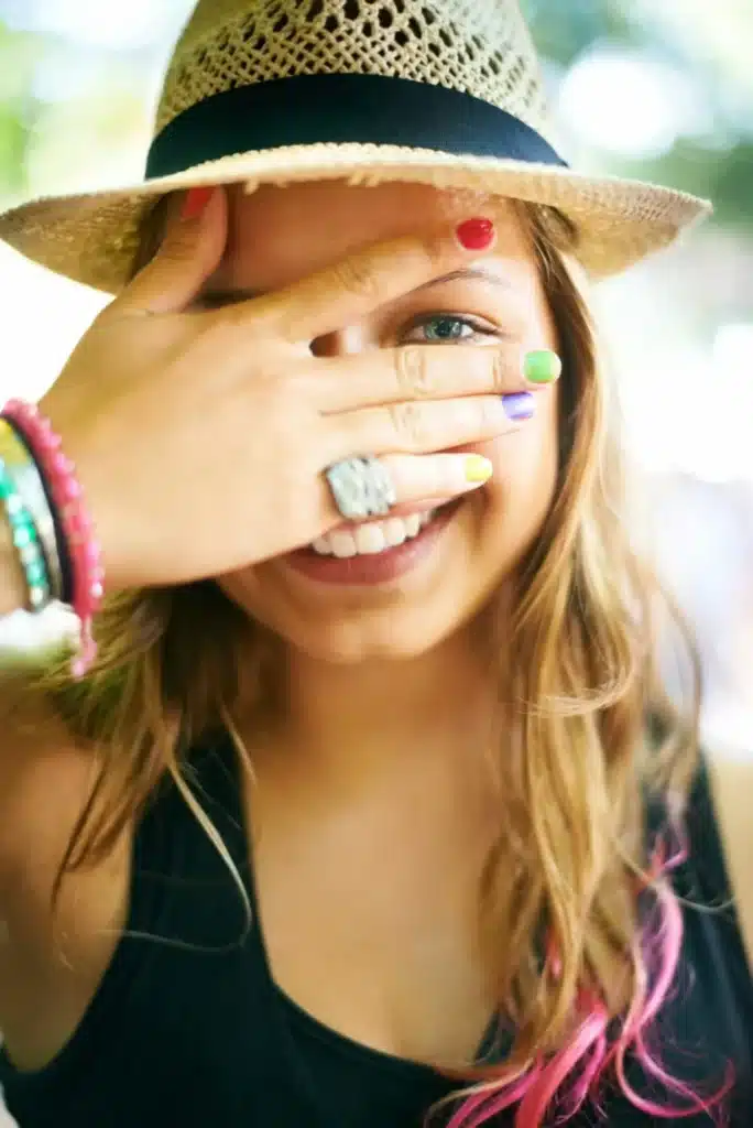 Why. A young woman wearing multi-coloured nail polish.