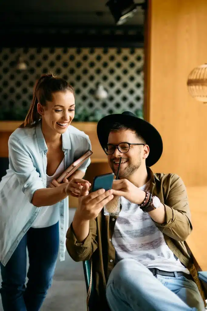 Young happy students having fun while using smart phone in a cafe,