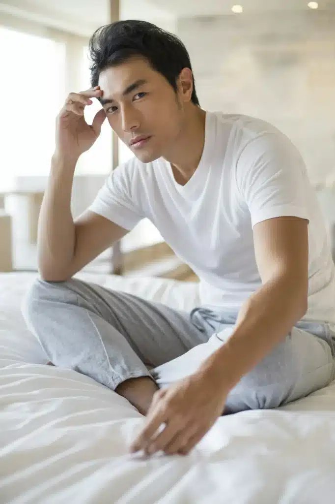 Young man sitting on bed