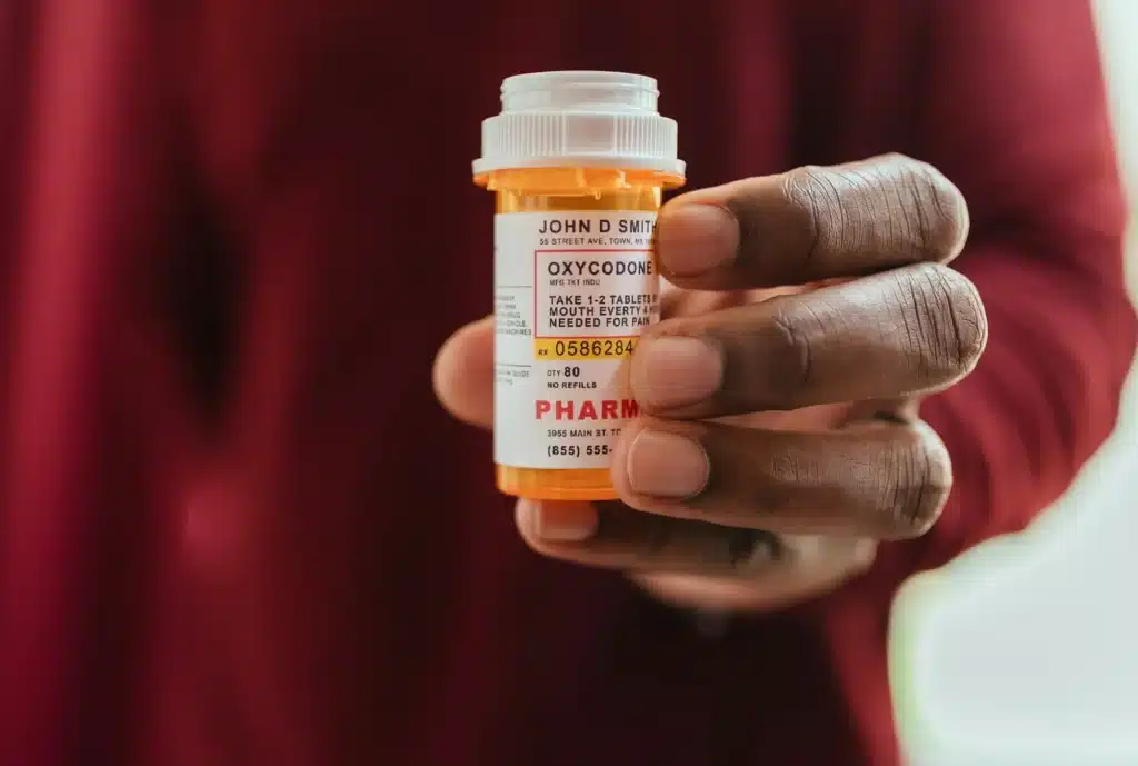 African American man I red shirt at home holding bottle of pain killer oxycodone