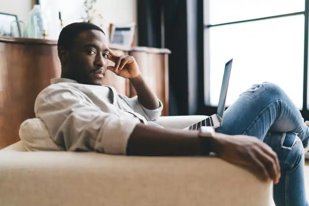 African American man sitting with laptop in sofa