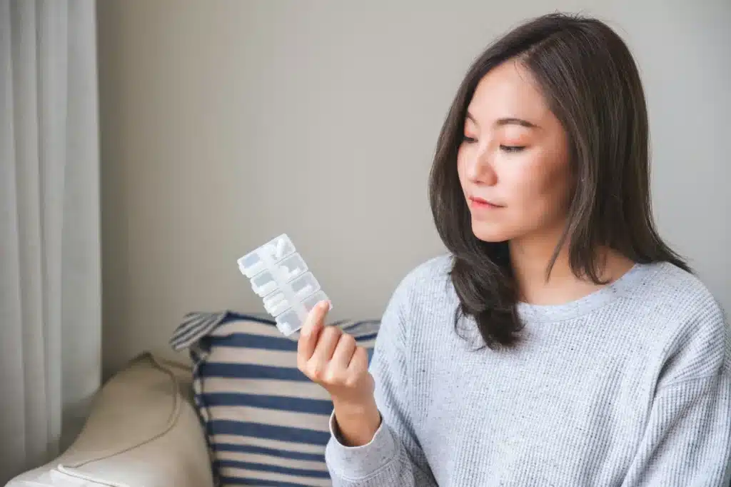 Portrait image of a woman holding and looking at pills box