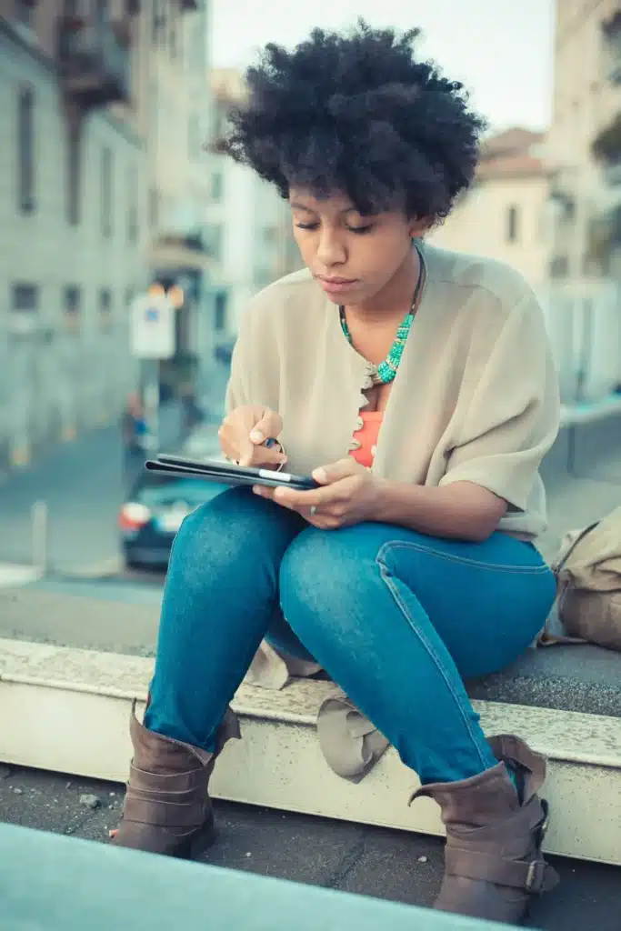 Young woman using touchscreen on digital tablet on edge of rooftop