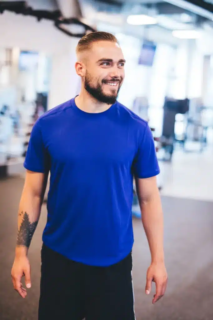 Smiling man standing in a gym.